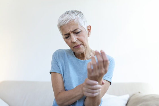 elderly woman suffering from pain hand arthritis old person senior woman female suffering from pain home 560x373jpg