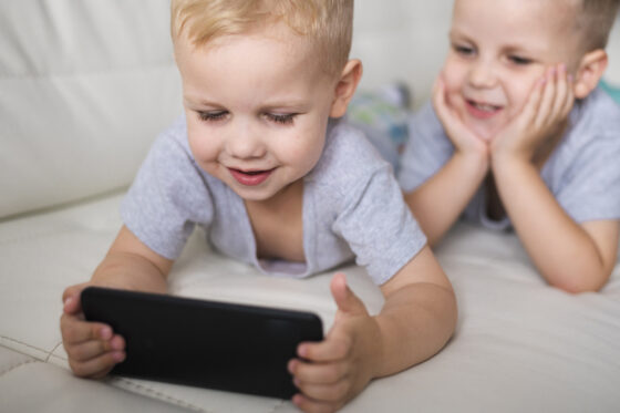 front view brothers playing smartphone 560x373jpg