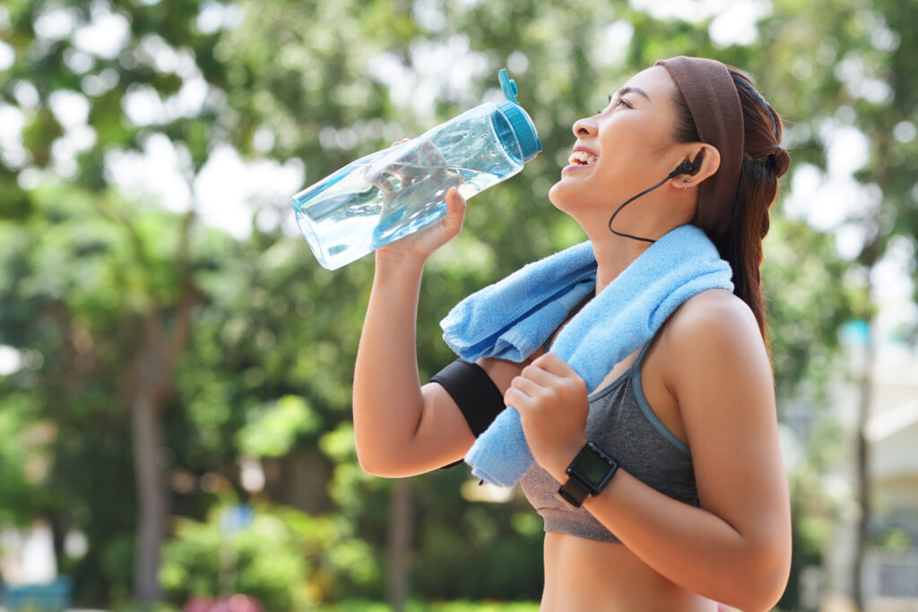 happy sportswoman drinking water in park 1024x683jpg