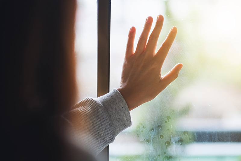 rear view image of sad woman touching on window while looking outsidejpg
