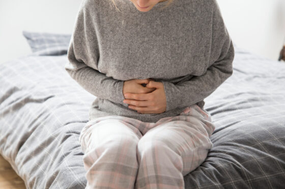 sick woman with hands stomach suffering from intense pain 1 560x373jpg