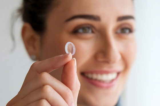 smiling woman holding contact lens tip her finger close her face 560x373jpg
