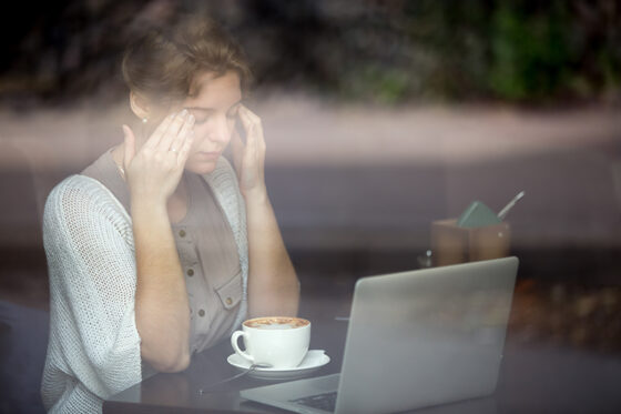young woman having headache shot through window 560x373jpg