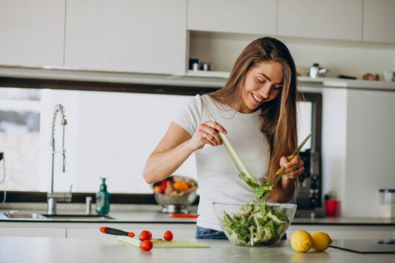 young woman making salad kitchen 560x373jpg